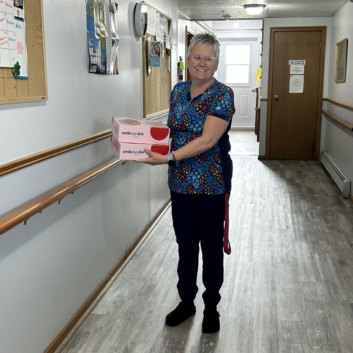 A staff member carrying a box of Smile Cookies down a hospital hallway